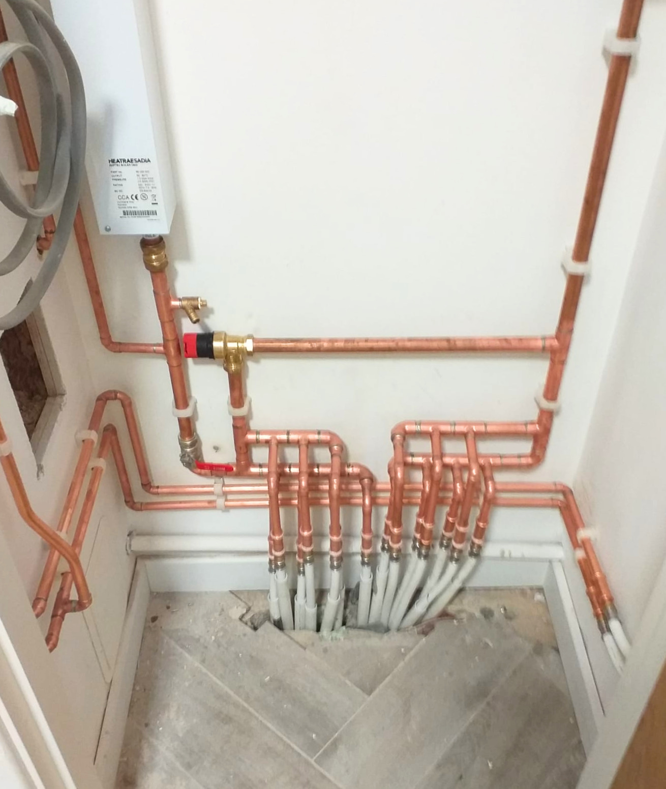First-fix copper and plastic pipework manifold in an airing cupboard in Ashford